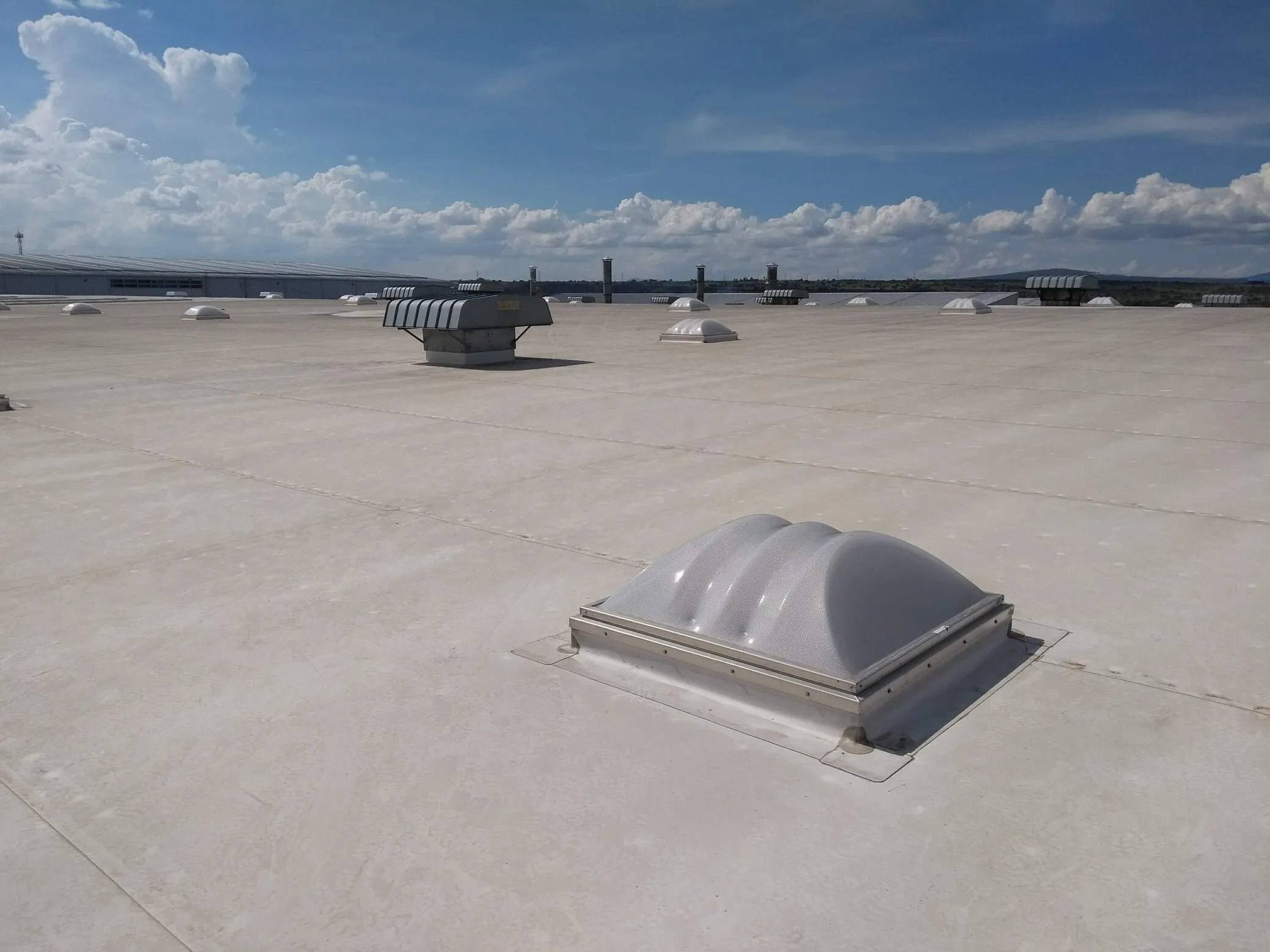 Vista interior de una tienda con techos altos y estructura metálica, donde se aprecian los domos que proveen iluminación cenital natural.