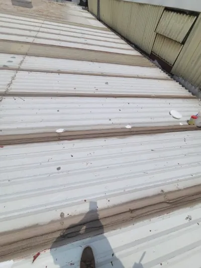 Primer plano de junta en cubierta metálica, mostrando sellador aplicado sobre suciedad y lista para instalar una membrana de PVC para sellado.