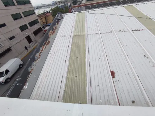 Múltiples juntas de techo metálico con acumulación de suciedad y puntos de sellado, indicando colocación futura de membrana de PVC.