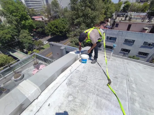 Especialista en seguridad realizando mantenimiento en la azotea, crucial para preservar la integridad de distintos tipos de cubiertas para techos en edificios.